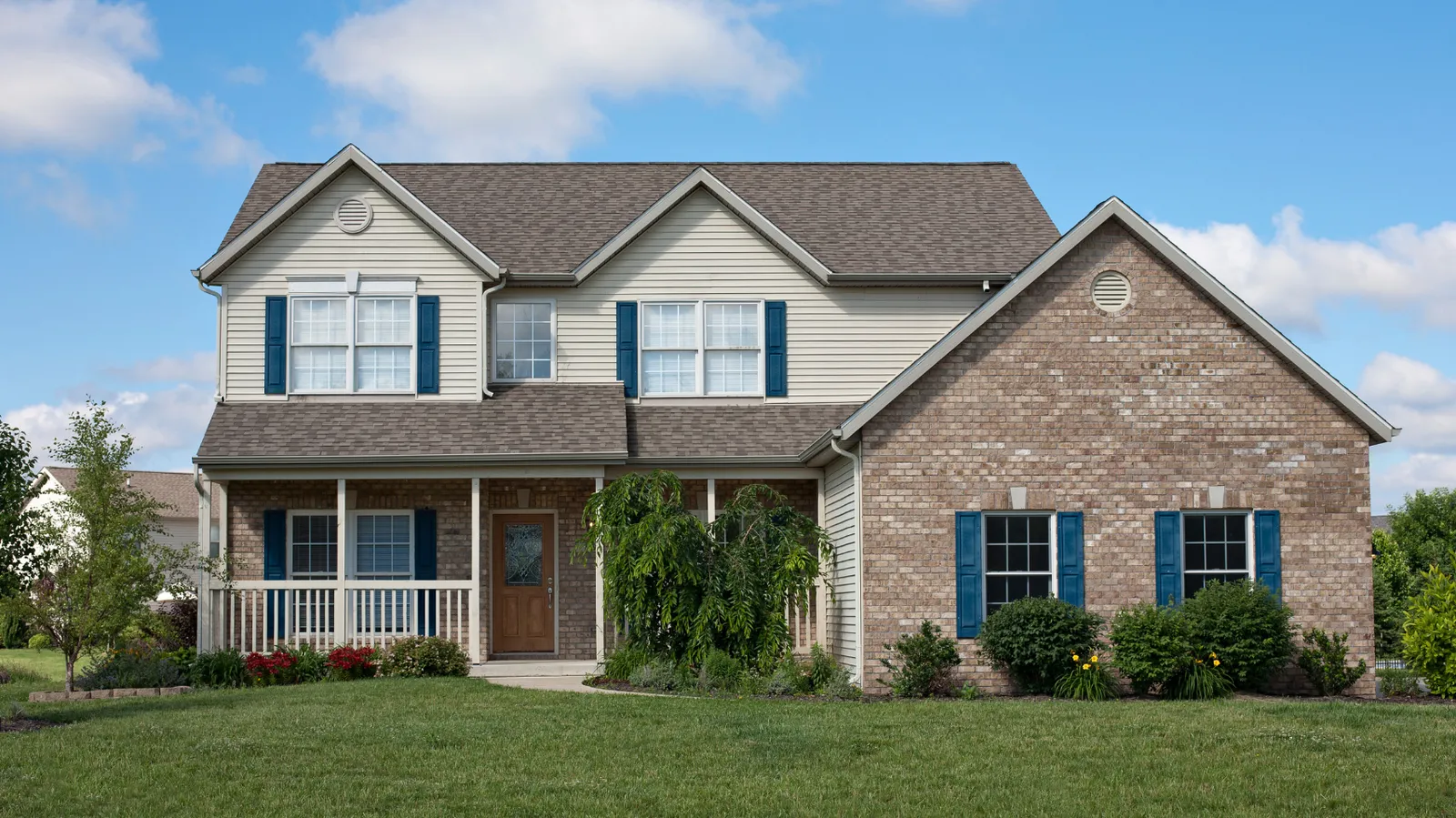 Two-story home of brick and siding under a brown shingle roof