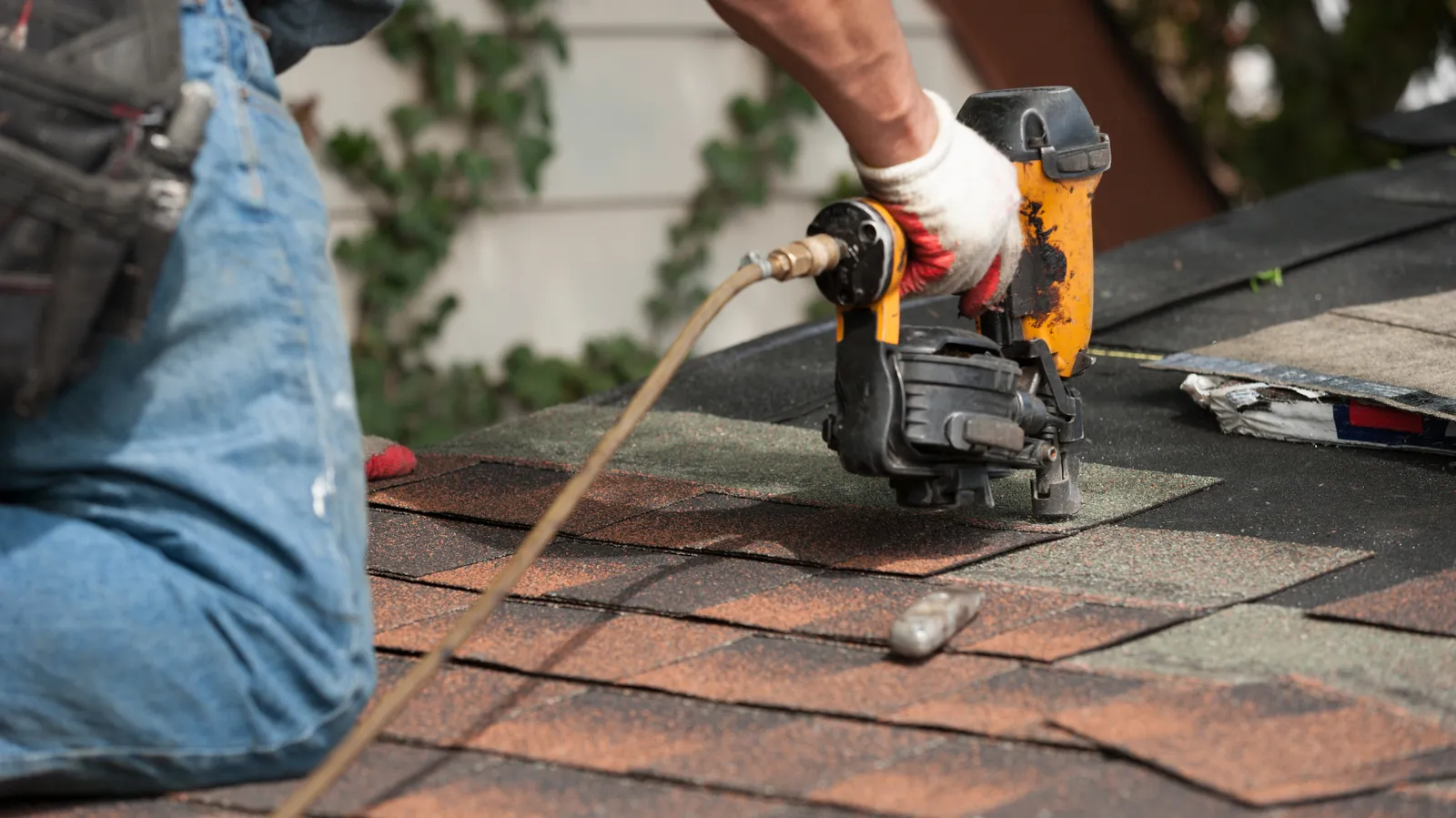 Shingles nailed by a gloved roofer with an air nailer